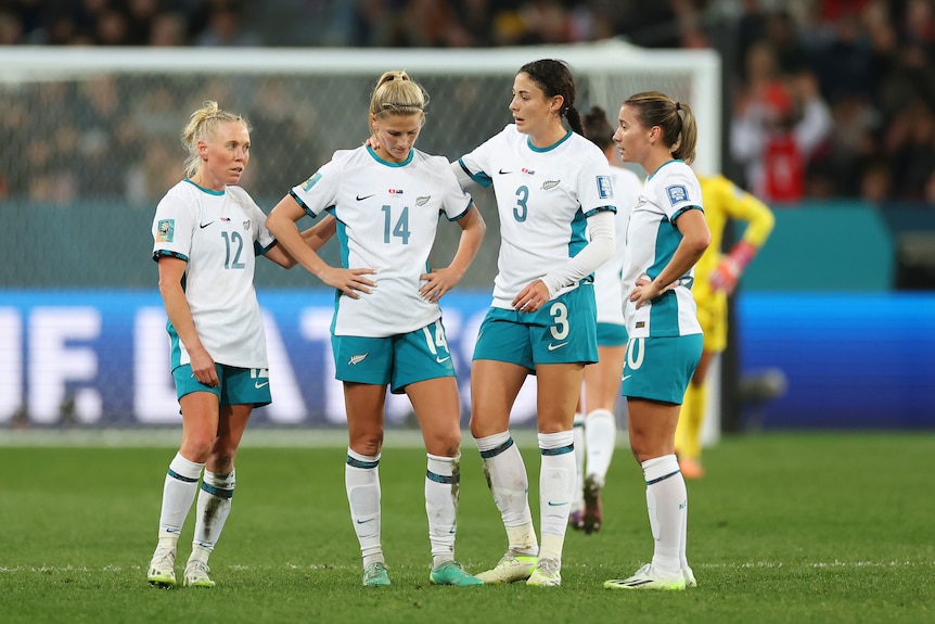 A group of New Zealand footballers look sad as they stand mid-pitch after a Women's World Cup game.