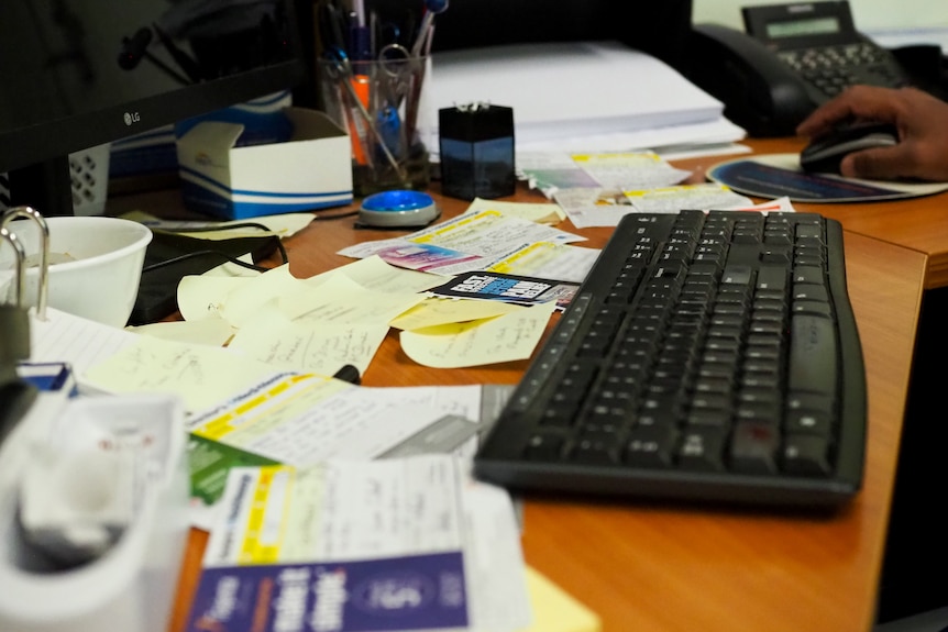 Papers, pens and a keyboard scattered on Dr Thevashangar Vasuthevan's desk