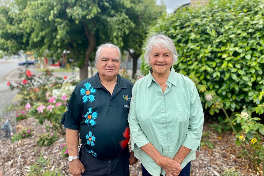 two people standing in front of a bush