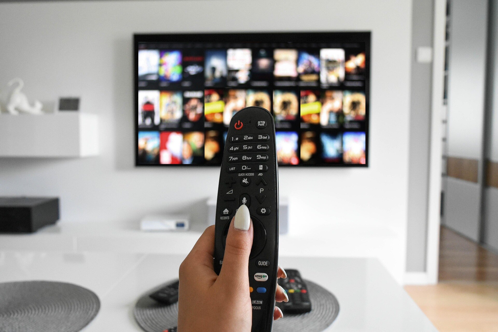 A person holds a remote control with a tv screen in front of them