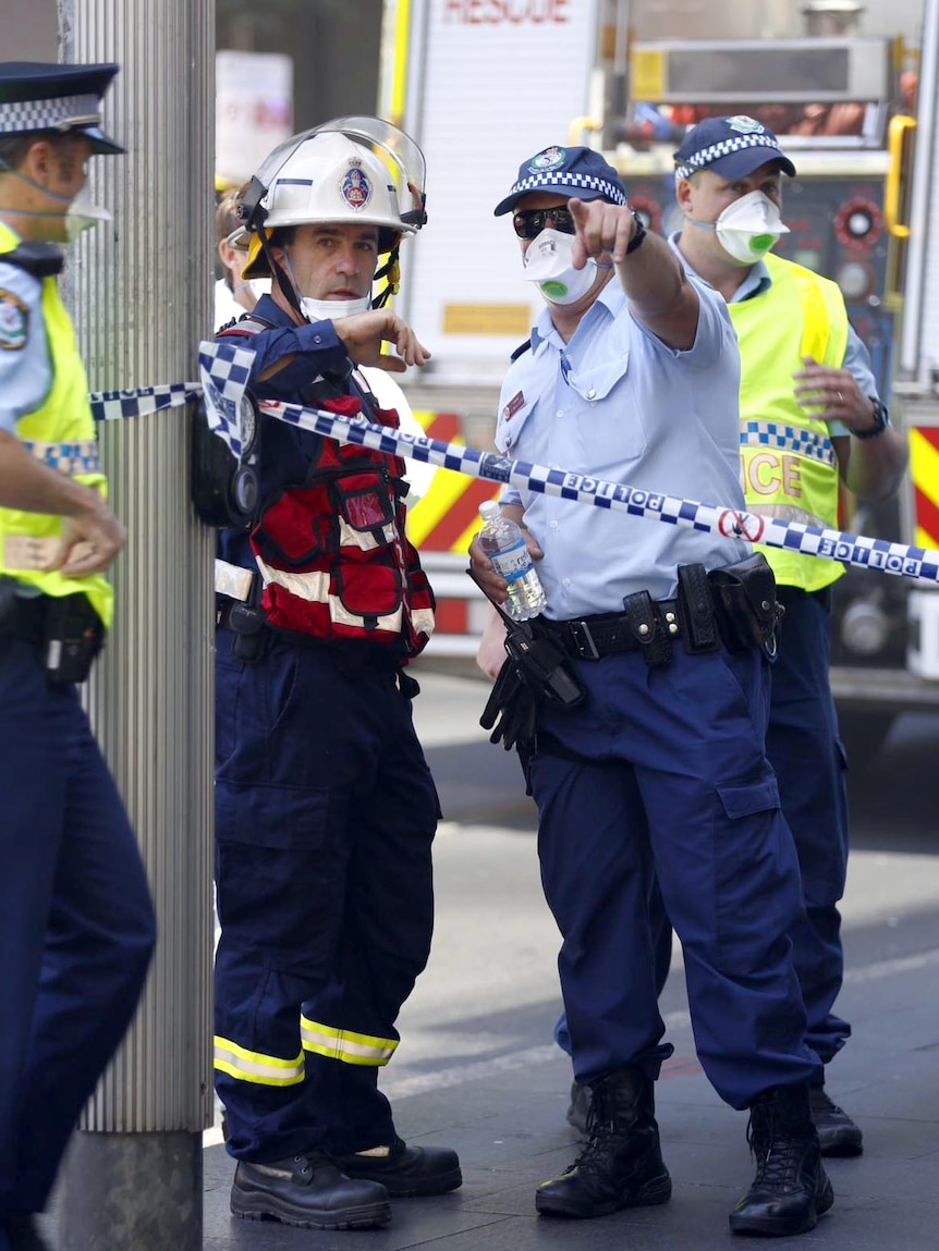 Police talk to firefighters at the scene of a fire in the Energy Australia building.