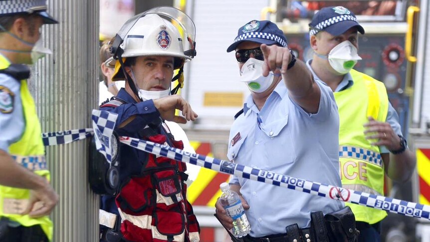 Police talk to firefighters at the scene of a fire in the Sydney Water Board building.