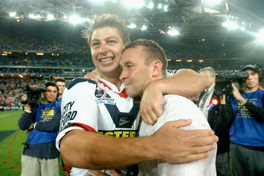 A coach and a player embrace after winning a grand final 