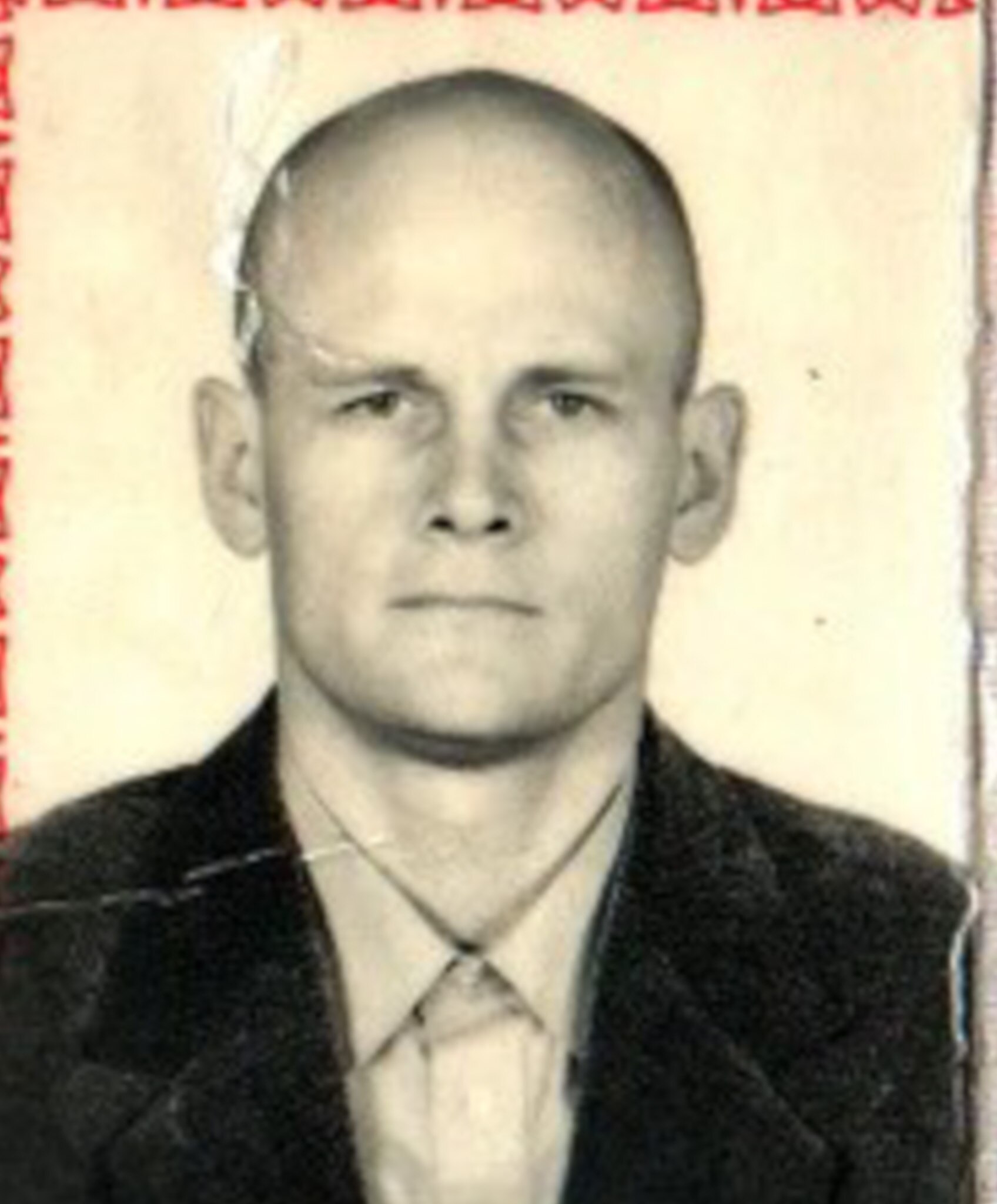 A slightly ripped passport photo shows a young bald man with stern expression