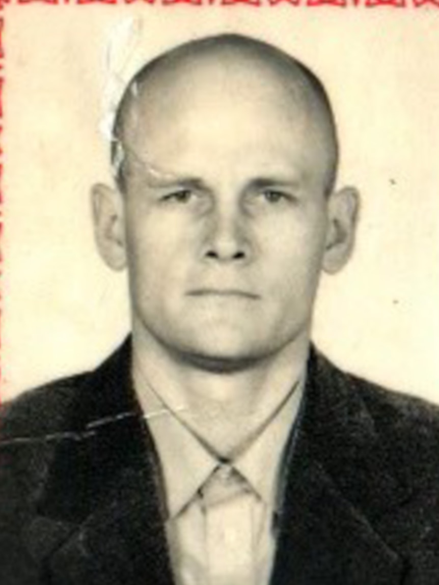 A slightly ripped passport photo shows a young bald man with stern expression