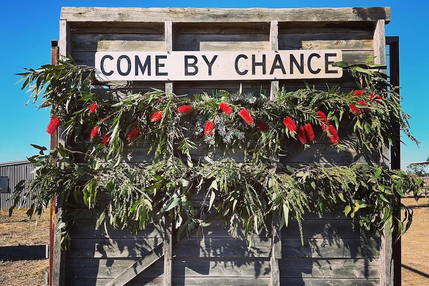 Flowers surround a town sign at the Come By Chance Race Course