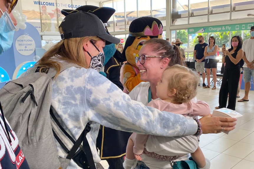 Malina Moore hugs with her sister Arna Milan who is holding her child Lucy at the airport. 