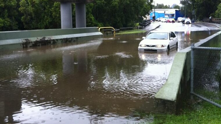A car makes its way through floodwaters at Deshon Street in the Brisbane suburb of Coorparoo.