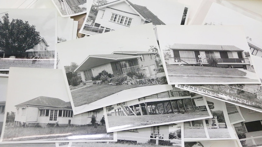 Some of the black and white photos in a pile on a table of Brisbane houses in the Corley collection.