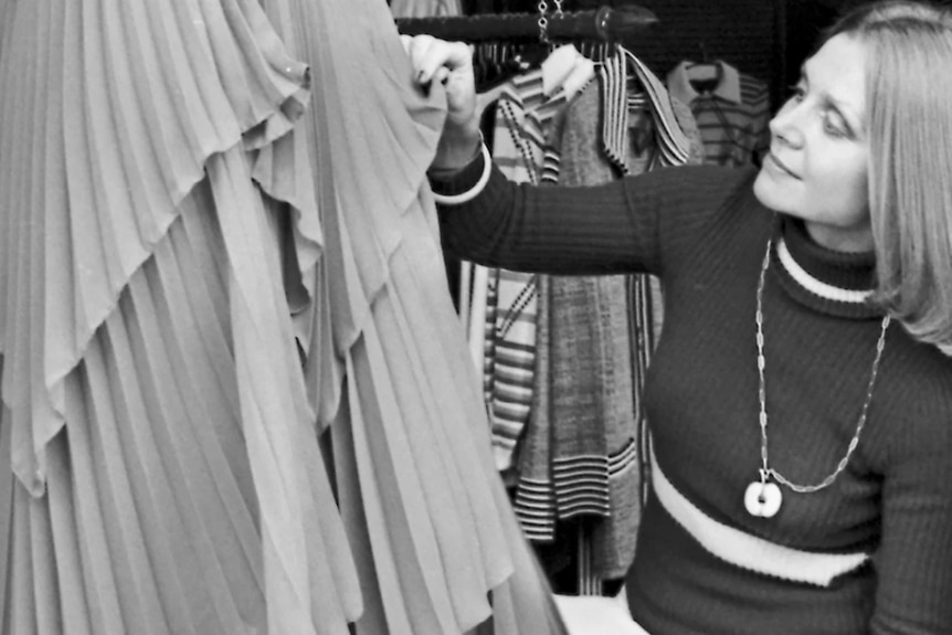 a woman looking at and holding pleated fabric