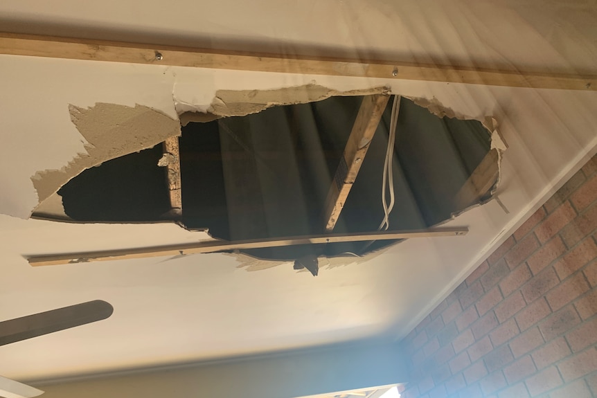 A close-up picture of a gaping hole in a ceiling.