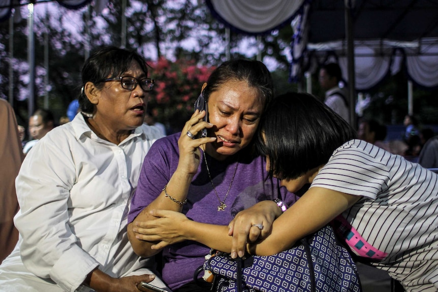 Three women are seen crying, one talking on phone.