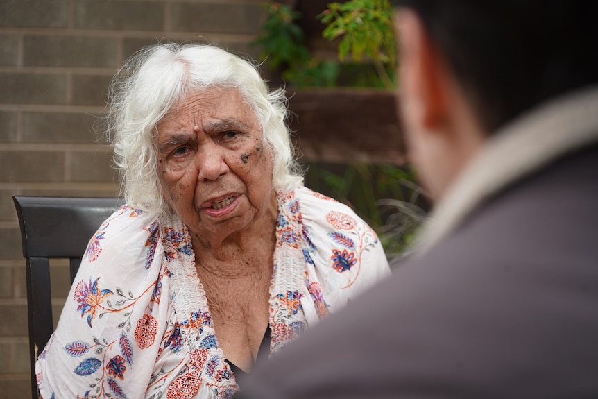 Una anciana indígena se sienta en una silla y habla con un periodista 
