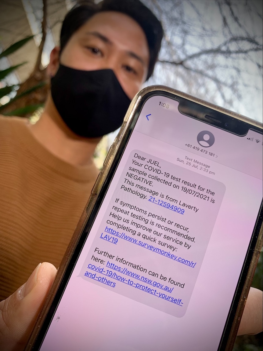 a man holding a phone that shows a test wait of six days for a covid test