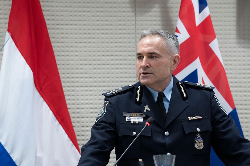 A man in police uniform stands at a lectern.
