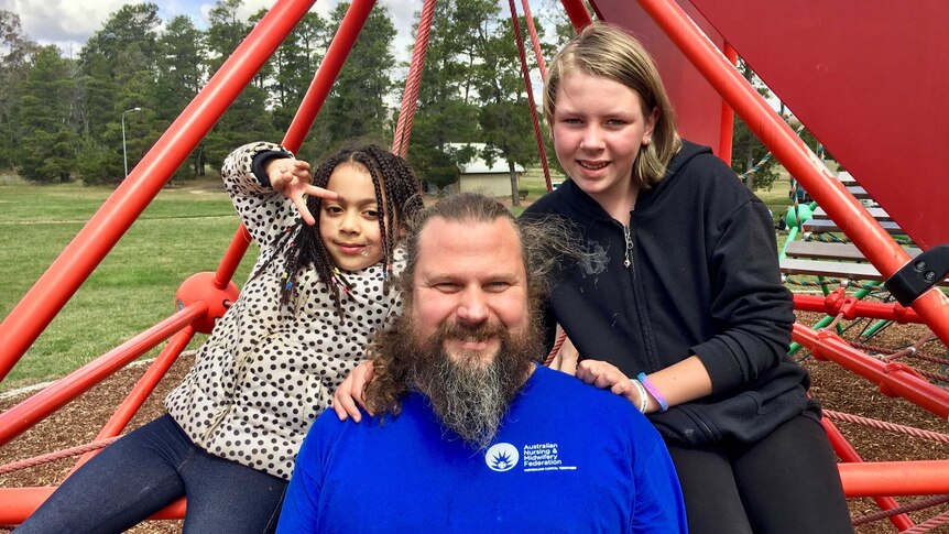 Shane Carter with his daughters at a park.