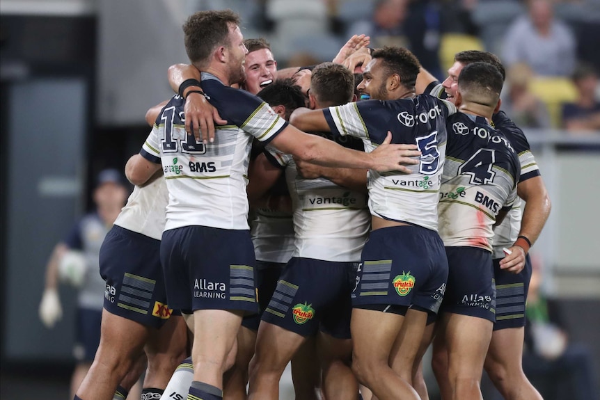 Several North Queensland Cowboys NRL players embrace as they celebrate a winning field goal against St George Illawarra.