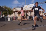 two men grinning wildly leap sprint across a finish line