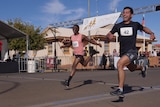 two men grinning wildly leap sprint across a finish line