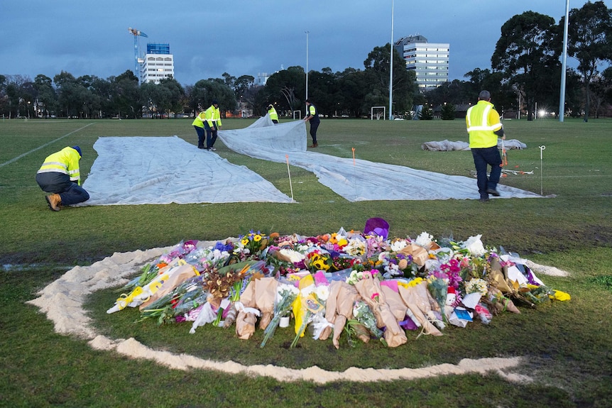 Council workers cover up graffiti painted at a makeshift memorial site for Melbourne comedian Eurydice Dixon.