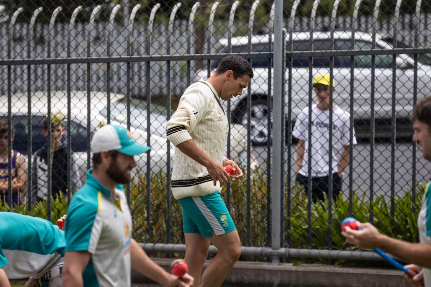 Scott Boland is watched by a young fan at cricket training.