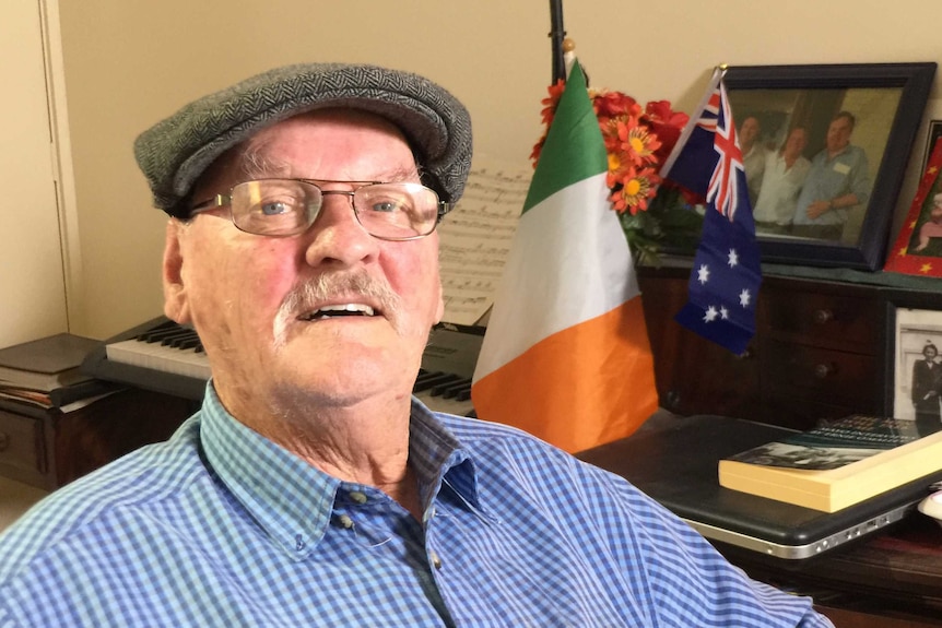 Paddy Cannon sitting looking at camera with an Irish flag in the background