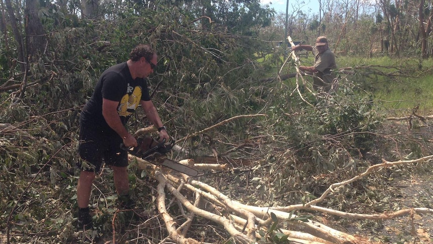 Byfield residents Peter Rose (foreground) and John Petty try to clear the town's main road of trees