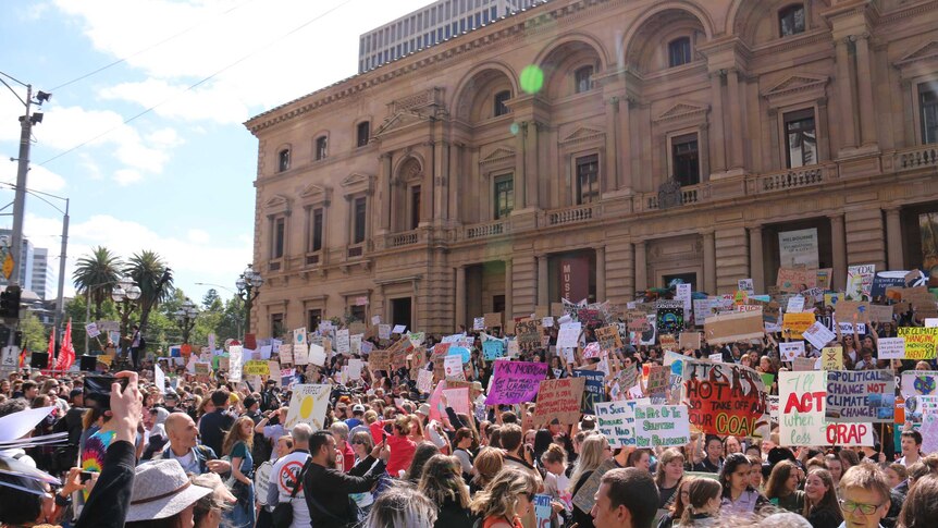 A crowd of thousands of student protesters with Victorian Parliament House in the background.