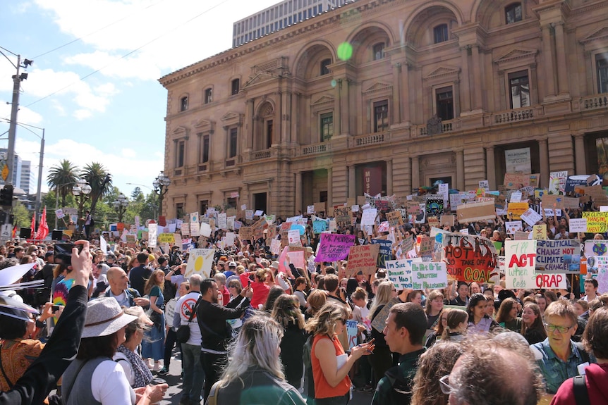 A crowd of thousands of student protesters with Victorian Parliament House in the background.