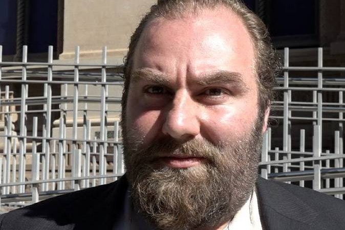 A close-up photo of Phillip Michael Galea, who has a brown beard, outside a court building.