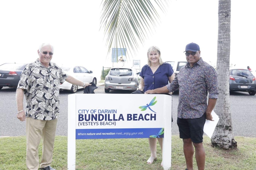 Three people unveiling a sign.