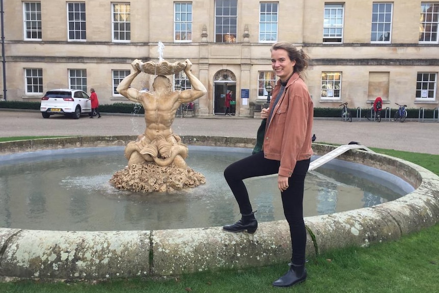 A happy young woman posing next to an Oxford fountain