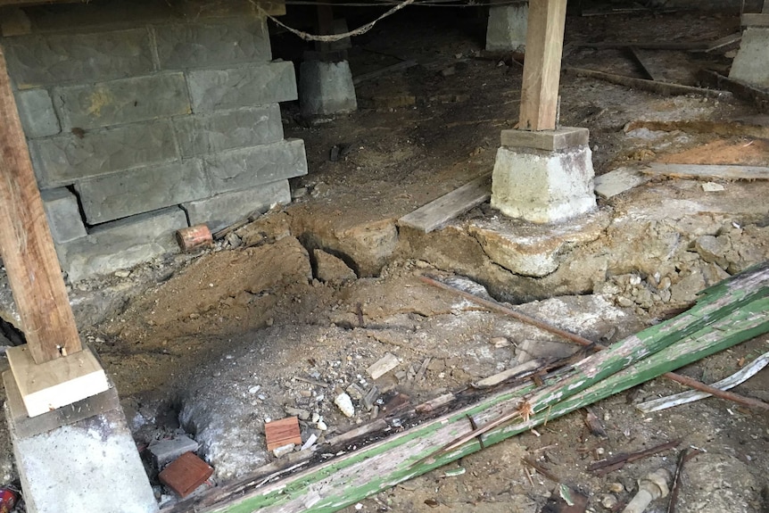 Cracks at the a bluestone house, pillars and mud can be seen.
