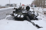 The turret from a military tank lies on a snow-covered road.