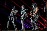 US band KISS performs on stage with black and white makeup on their face.