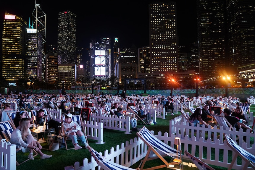 Oameni care stau la AIA Vitality Park pentru a viziona un film în aer liber în Hong Kong