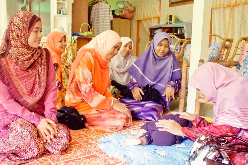 A group of women seeing a baby sleeping