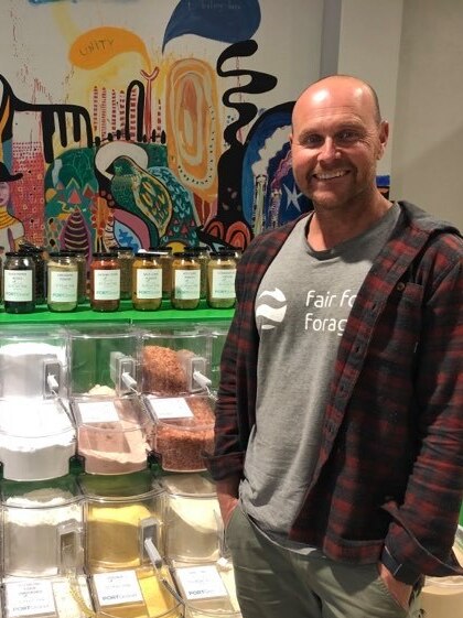 A man stands in front of bulk-food dispensers.