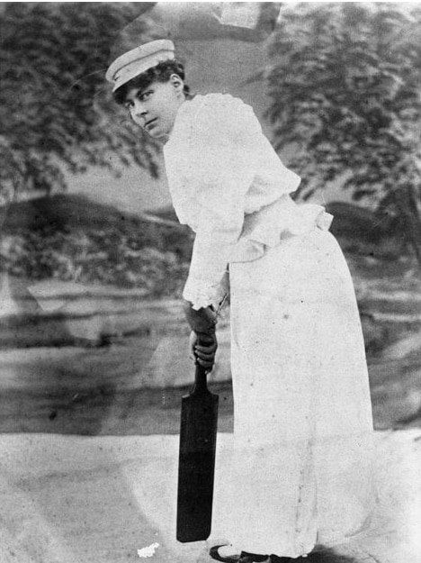 Nellie Gregory poses with a cricket bat at the Sydney Cricket Ground, wearing a white outfit and cap.