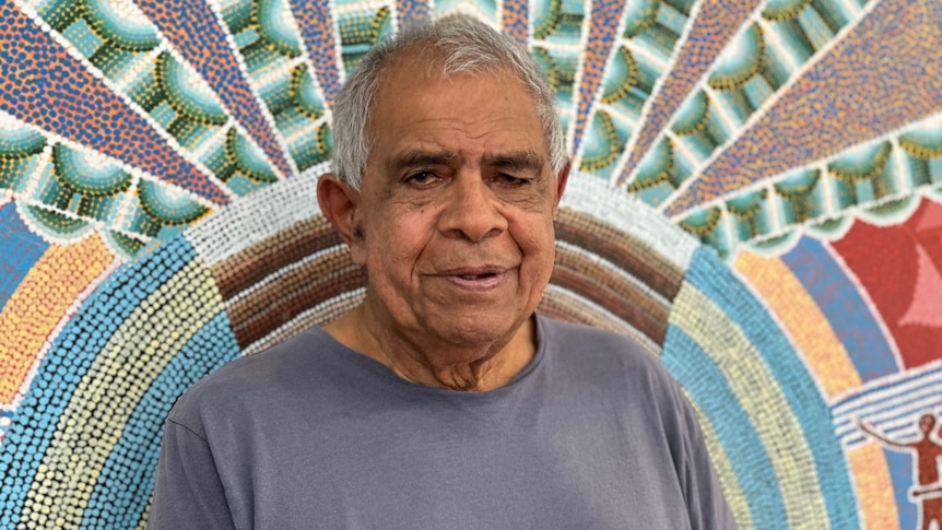 Uncle Gary Williams stands in front of an Indigenous mural at the Muurbay Language Centre