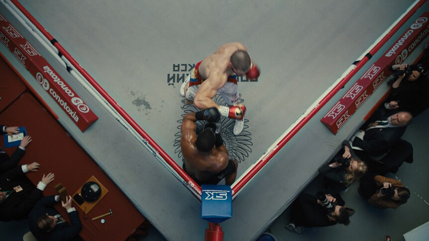 Colour aerial still of Florian Munteanu and Michael B Jordan boxing in 2018 film Creed II.