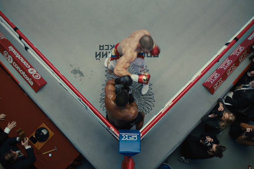 Colour aerial still of Florian Munteanu and Michael B Jordan boxing in 2018 film Creed II.
