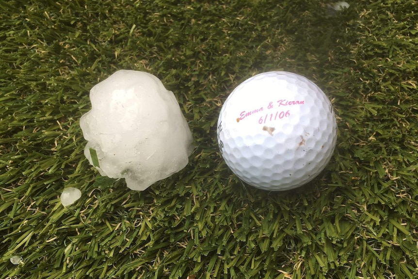 a hail stone sits on grass next to a golf ball