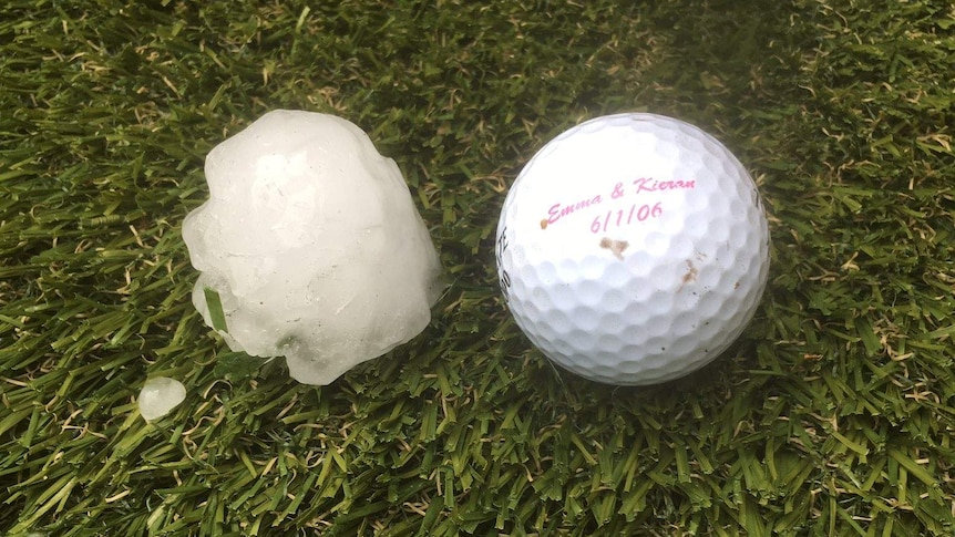 a hail stone sits on grass next to a golf ball