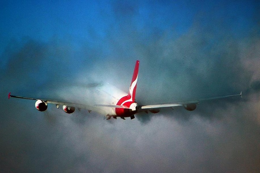 A Qantas flight disappears into the clouds above Melbourne airport.
