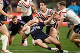 A man grimaces after a high tackle in a rugby league match