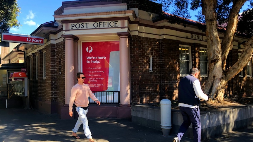 A post office with two people walking past.