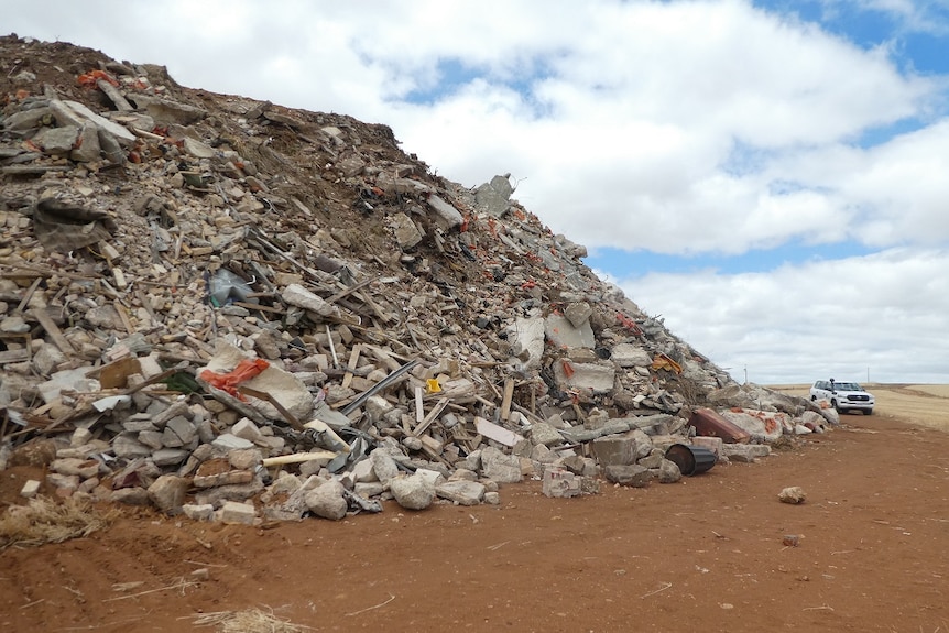 A large pile of pieces of concrete next to a four-wheel drive