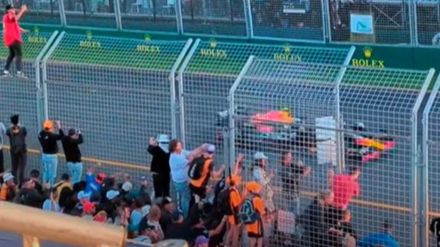 A screenshoot of fans climbing on safety fencing.