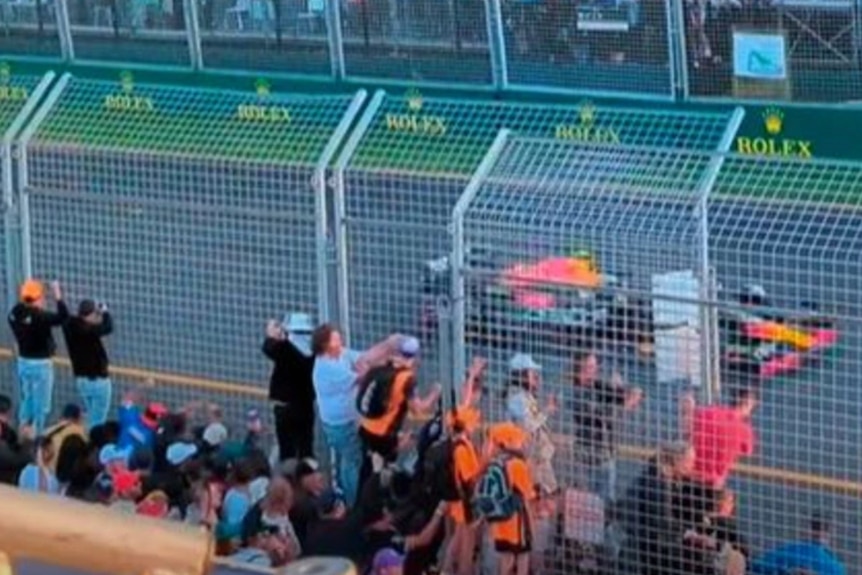 A screenshoot of fans climbing on safety fencing.